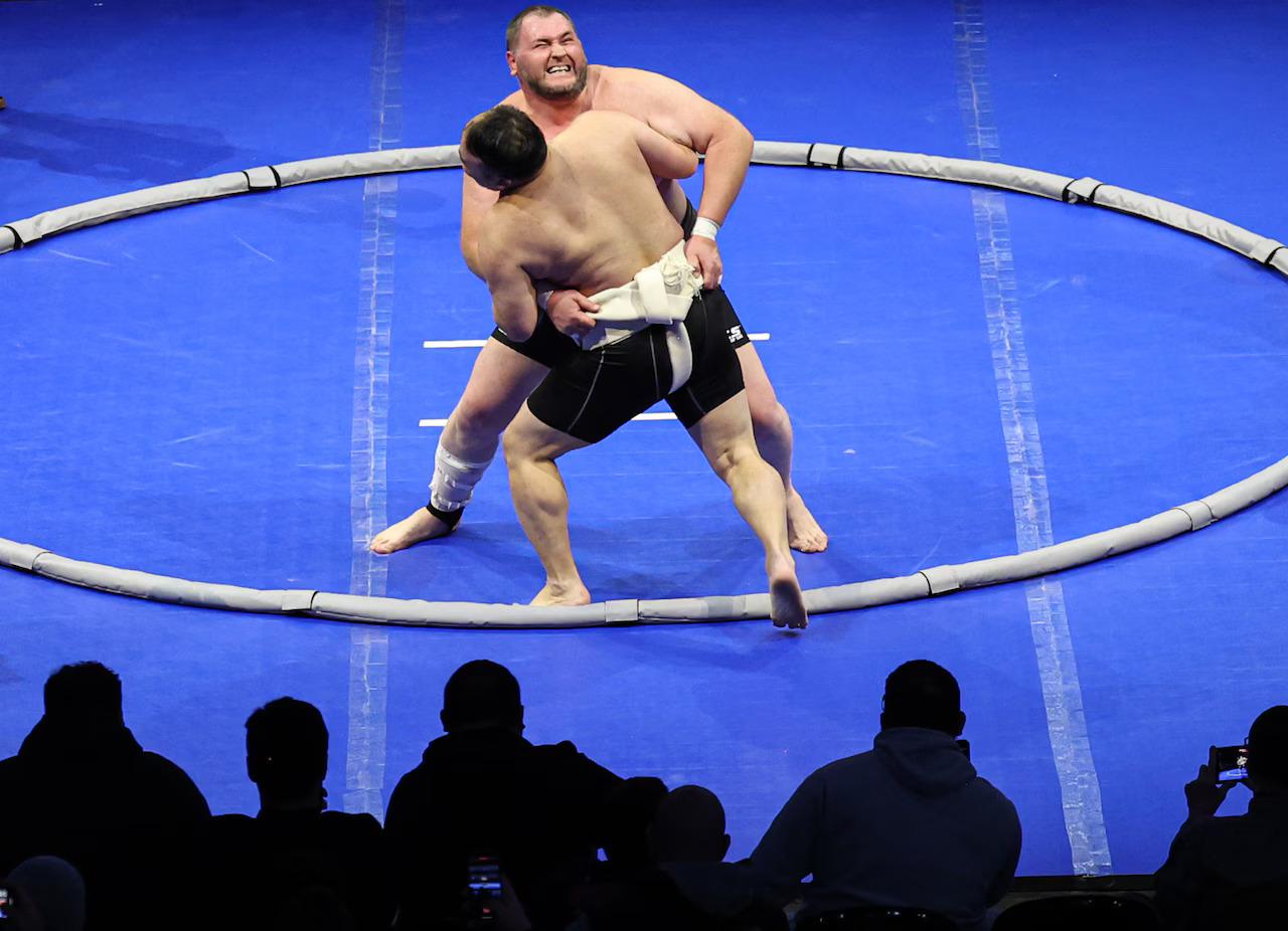 Two rikishi grappling at the edge of the ring