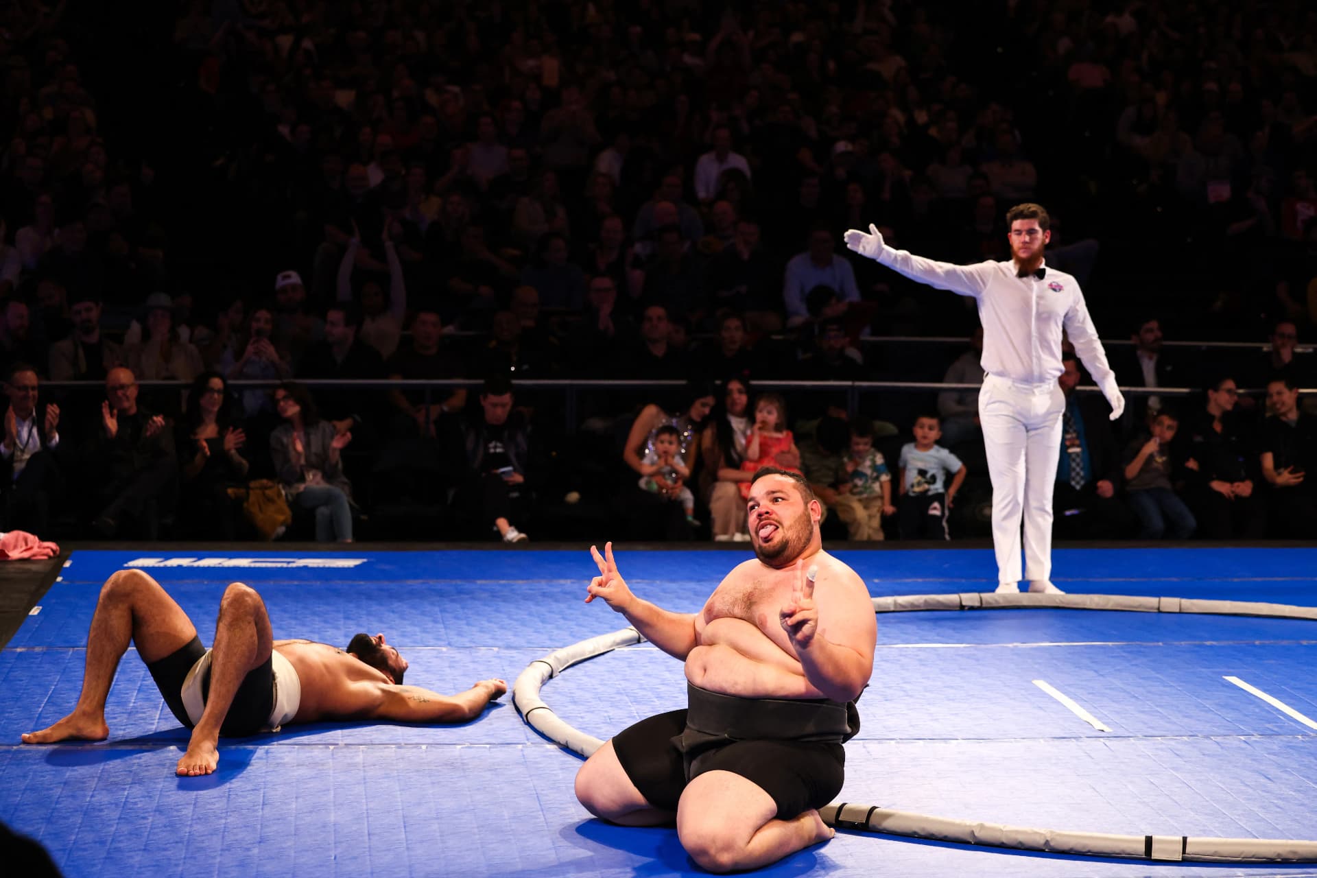 Winning rikishi celebrating beside his fallen opponent